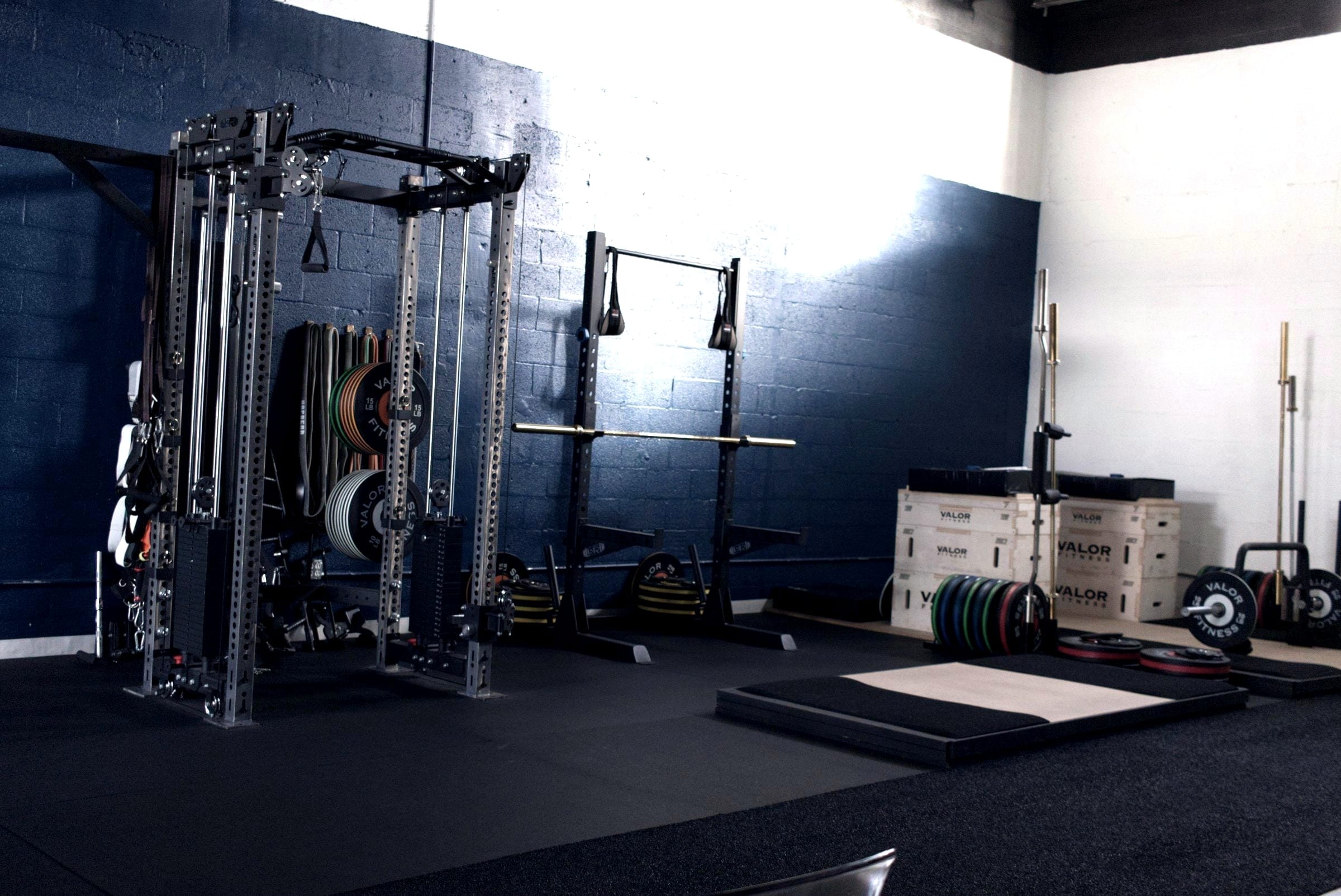 Um espaço de treino a ser montado: racks, uma plataforma e caixas de material por abrir.