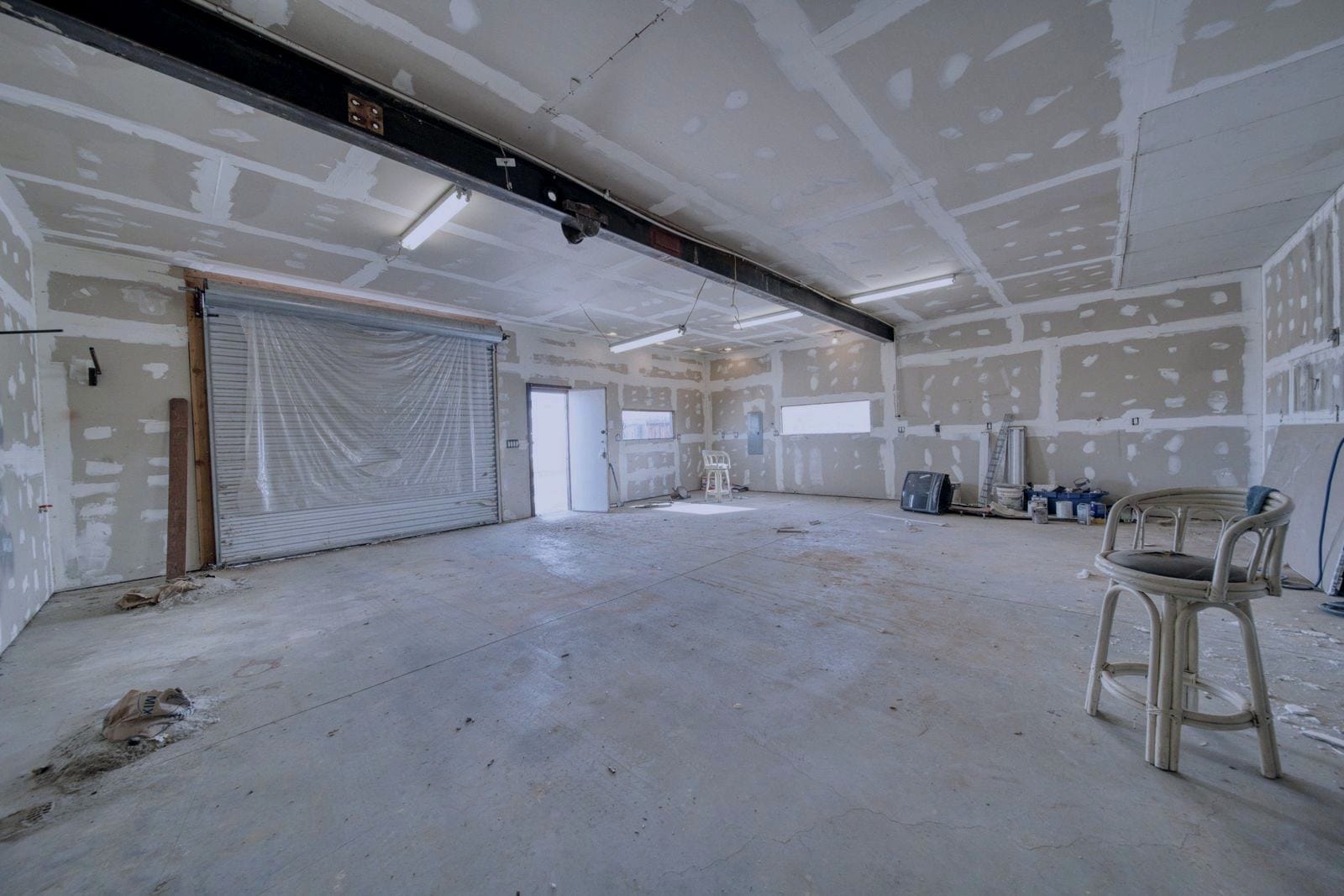 Commercial unit under construction, with unpainted drywall and a roll-up door at the back.